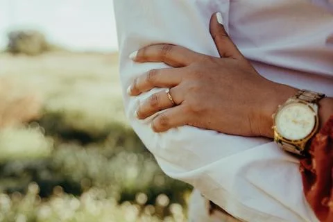 A woman's hand with a ring rests on her husband's arm, sharing a tender moment. Stock Photos