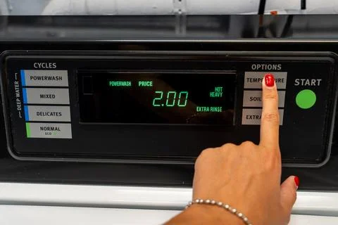 Woman's hand selecting the washing temperature on a top-loading machine Stock Photos