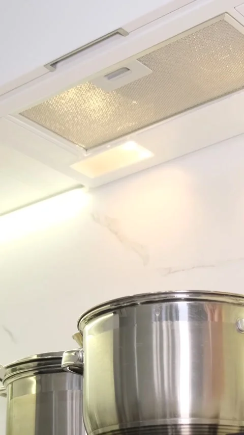 A woman's hand selects a mode on the hood, stands near a kitchen appliance in a Stock-Footage 250382325