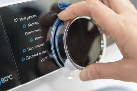 Woman's hand selects the washing mode with a round selector Stock Photos