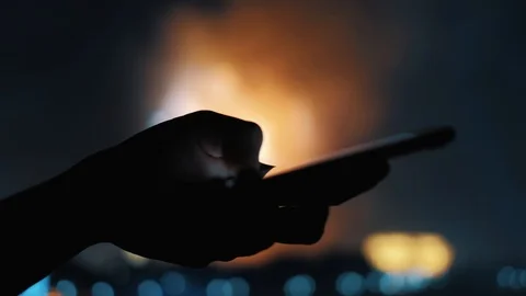 Woman's hand sending a message on a mobile phone with fireworks in background Stock Footage 92200500