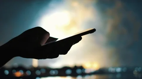 Woman's hand sending a message on a mobile phone with fireworks in background Stock Footage 92200573