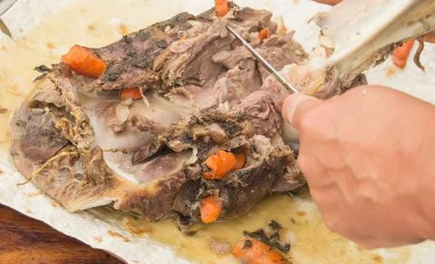 A woman's hand separates the fried meat from the bones, cutting it with a kni Stock Photos