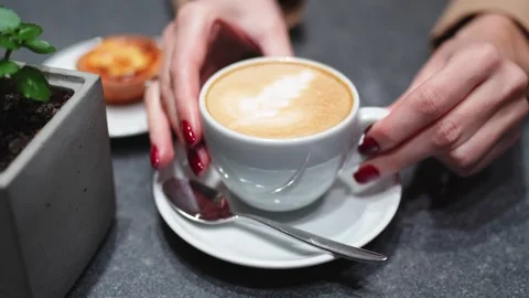 Woman’s hand serving a cup of coffee with milk, accompanied by a pastry. Stock Footage 292918198