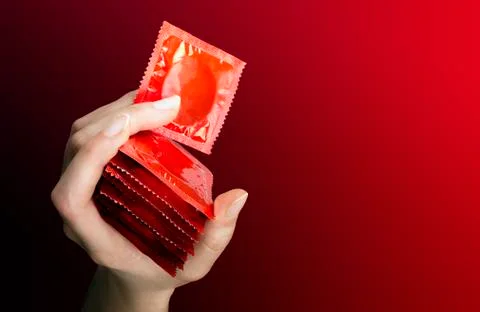 Woman's hand with seven  red  condoms Stock Photos