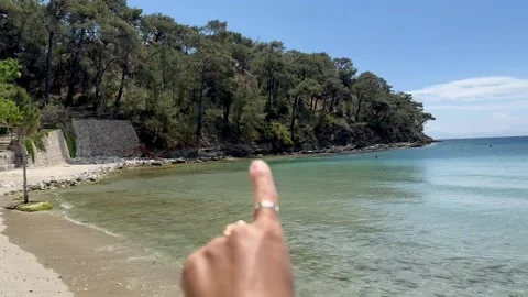 A woman's hand shows that there is a path along the shore. Greece. Stock Footage 288841674