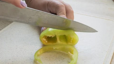 A womans hand slices a yellow pepper into rings on a board Stock Footage 319954561
