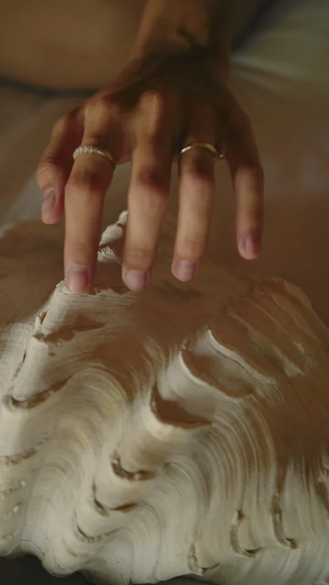 A woman's hand slowly strokes a large seashell, vertical video Stock Footage 274634145