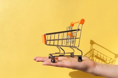 On a woman's hand is a small empty metal trolley from a supermarket Stock Photos
