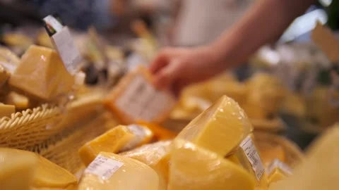 A womans hand sorting through cheese lying on a grocery store counter and Vídeo Stock 313189836