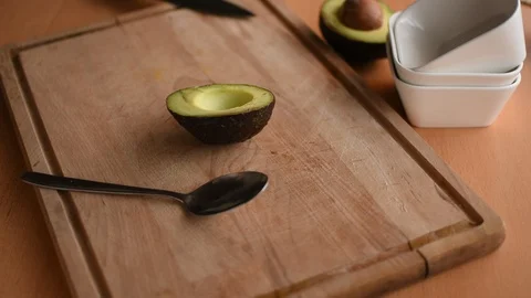Woman's hand spooning out half of an avocado Vidéo 123146431
