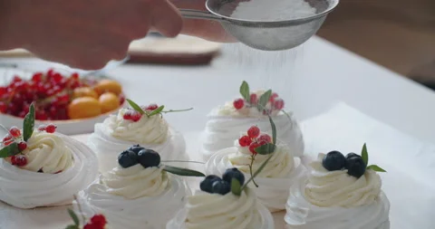 Woman's hand sprinkle icing sugar over fresh desserts. Stock Footage 161192336