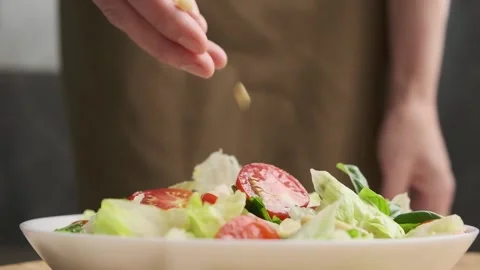 Woman's hand sprinkles pine nuts salad. Stock Footage 157741088