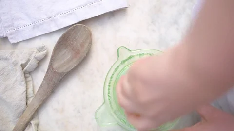 Woman's hand squeezing fresh lemon juice with squeezer Stock Footage 76100012