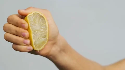 Woman's hand squeezing a half of a lemon. Half of juice lemon in hand. Stock Footage 132909063