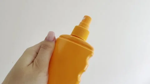 Woman's hand squeezing a yellow sunscreen spray bottle against a white back.. Stock Footage 335139537