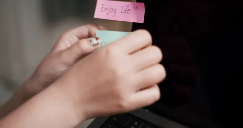 A woman's hand sticks a note with a message on a laptop screen. Stockbeeldmateriaal 313868293