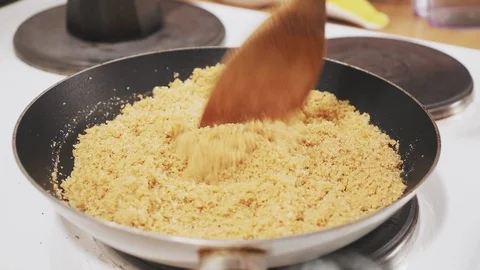 Woman's hand stirring bread crumbs with butter in a pan on the stove Stock Footage 121294919