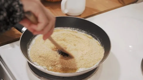 Woman's hand stirring bread crumbs with butter in a pan on the stove Stock Footage 121294988