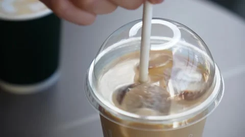 A woman's hand is stirring an ice latte. Close-up Stock Footage 280438034