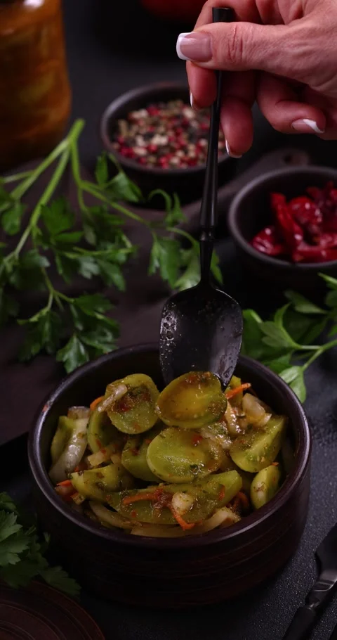 Woman's hand stirring pickled green tomatoes with spoon Stock Footage 324516225