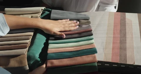 A woman's hand strokes the fabric samples that the designer holds next to the Stock Footage 159783025