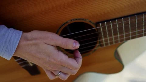 A woman's hand is strumming the strings of a guitar. Close-up Stock Footage 305231537