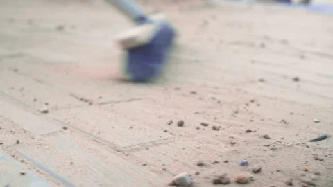 A woman's hand sweeps sand on the gray surface of concrete slabs with a broom Stock Footage 156038413