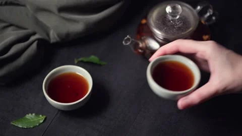 A woman's hand takes a ceramic mug and drinks hot black tea. Tea ceremony Stock Footage 143992204