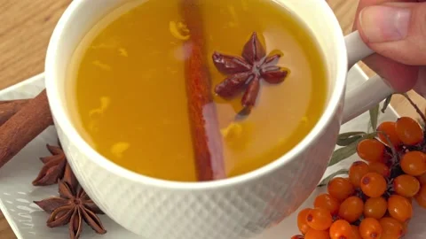 Woman's hand takes a cup hot healthy fruit tea from sea buckthorn from a teapot Stock Footage 214264205