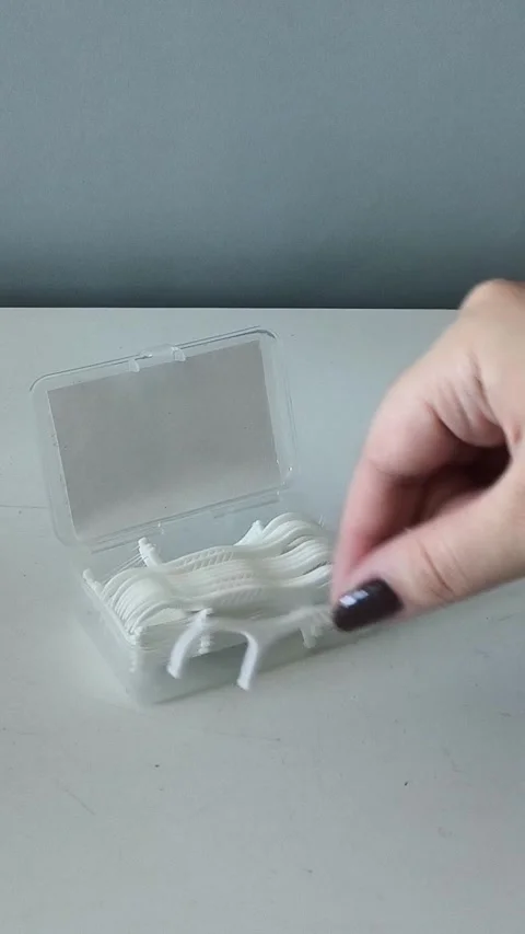 A womans hand takes the flosser from the container and places it on the table Stockbeeldmateriaal 329969457