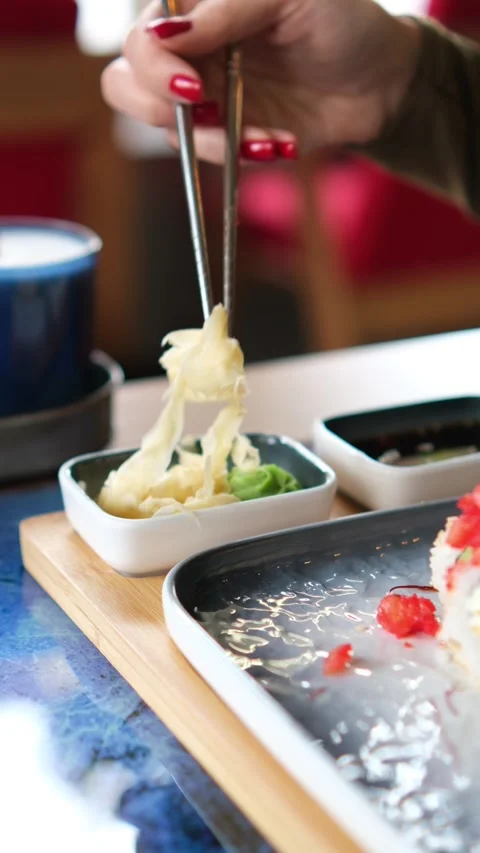 A woman's hand takes ginger using sushi chopsticks. Close-up. Vertical video. Stock Footage 269506734