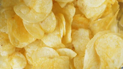 A woman's hand takes one crispy snack. A pile of unhealthy food lies on the Stock Footage 219755155