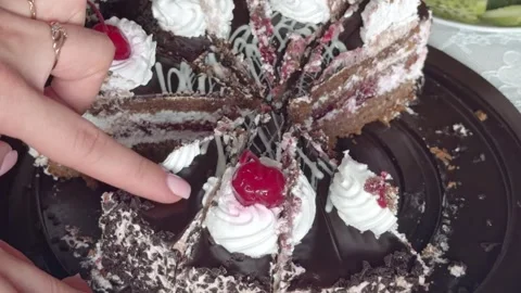 Woman's hand takes a slice of chocolate cake with cherry and whipped cream .. Stock Footage 337883042