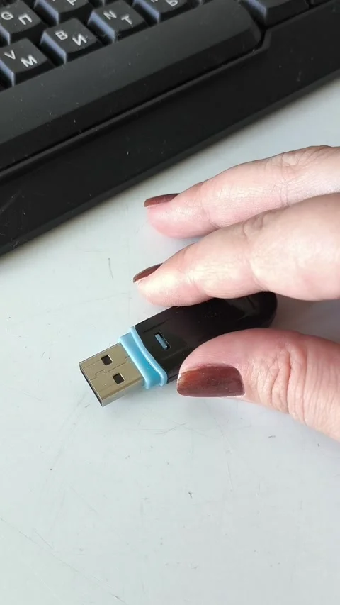 A womans hand takes a USB flash drive from the table, next to it is a laptop Stock Footage 320523702