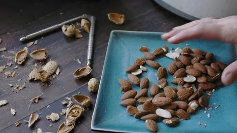 Woman's Hand taking almonds from a plate Stock Footage 75759568