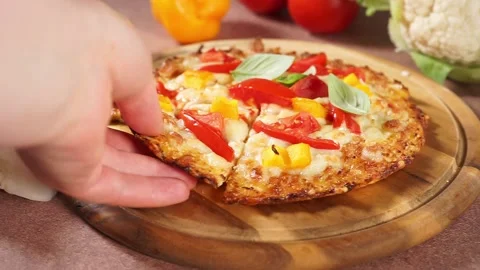 Woman's hand taking a slice of hot cauliflower pizza with a lot of melted cheese Stock Footage 137096330