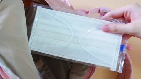 Woman's hand taking a surgical face mask from inside a backpack Stock Footage 194467607