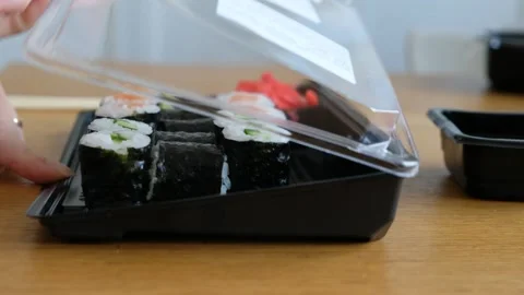 Womans hand taking sushi rolls from plastic box, japanese food delivery service Stock Footage 130653574