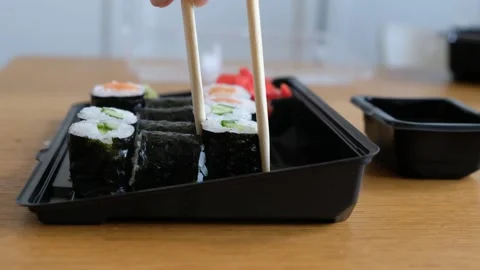 Womans hand taking sushi rolls from plastic box, japanese food delivery service Stock Footage 130967065