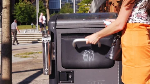 Woman's hand throwing away garbage in public trash can Stock Footage 97285004