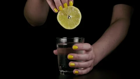 A woman's hand throws a lemon into a glass. Slow motion Video stock 76155861
