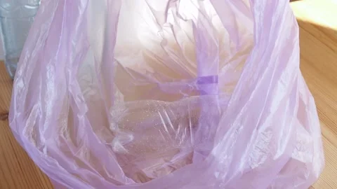 Woman's hand throws a plastic bottle into a garbage bag Stock Footage 219915845