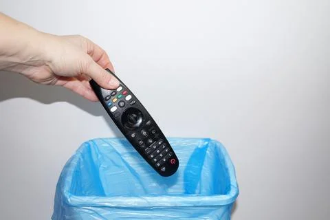 A woman's hand throws the TV remote control into the trash can close-up Fotos Stock