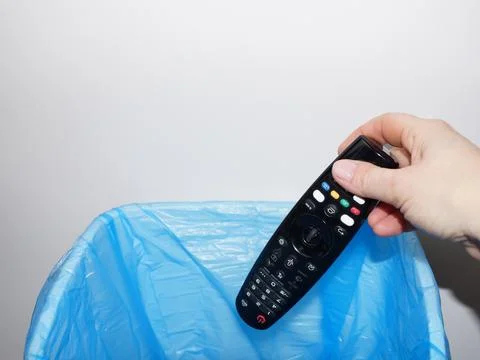 A woman's hand throws the TV remote control into the trash can close-up Fotos Stock