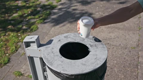A woman's hand tosses a to-go coffee cup into a trash bin, let's halt planet Stock Footage 244933232