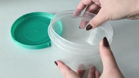 A womans hand touches the edge of a plastic container with her finger Vidéo 330156745