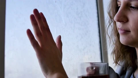 The woman's hand touches the window pane, which is frozen over, and with her Stock Footage 145071470