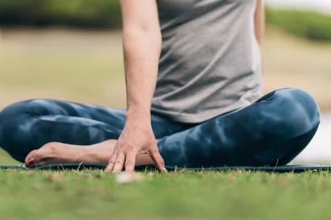 Woman's hand touching the grass while doing yoga outdoors Stock Photos