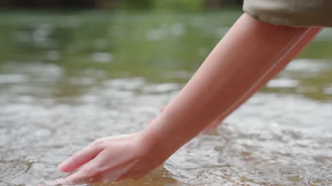 A woman's hand touching the surface of river she feeling relaxed. Video stock 254716559